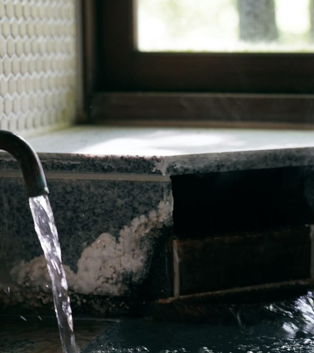 a faucet with water running out of it next to a window